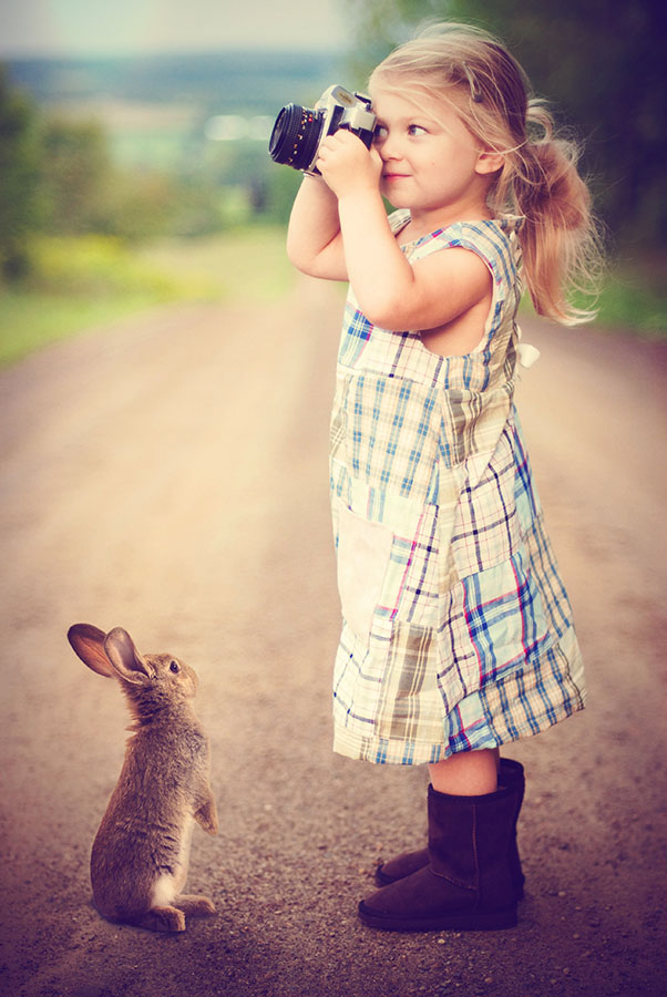 Niña con cámara mientras le mira un conejo